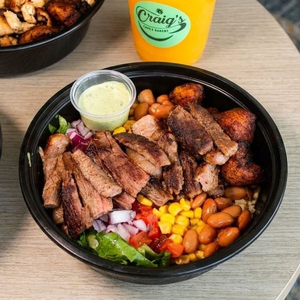 Three bowls of food, one with steak, one with shrimp, and one with chicken, on a wooden table.